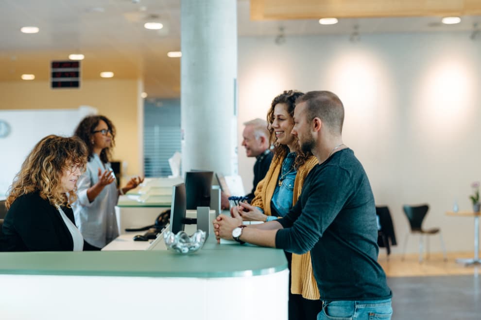 People being helped at a desk. 